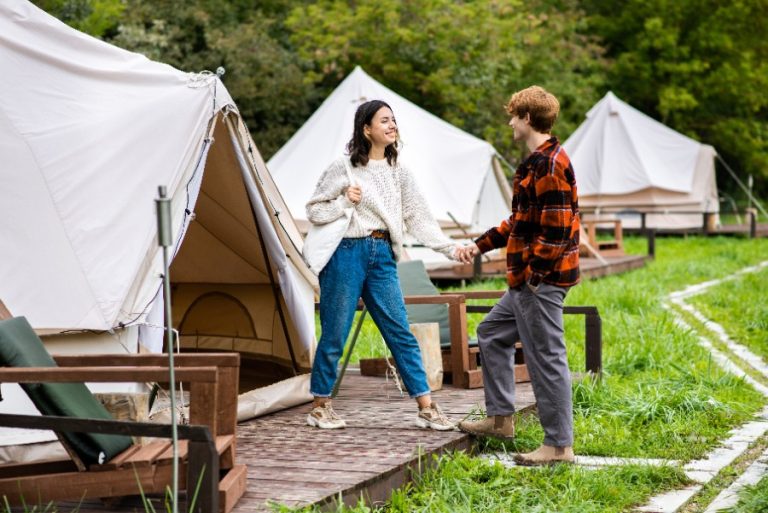 Tente de glamping en toile beige avec lit double, terrasse en bois et vue sur les montagnes d’Auvergne