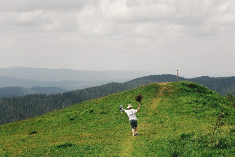 Randonneurs avançant sur un sentier de crête face aux volcans d’Auvergne sous un ciel dégagé