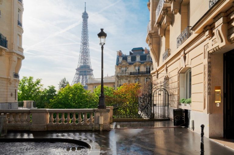 Façade illuminée d’un palace parisien avec ses balcons dorés et son entrée majestueuse bordée de lanternes