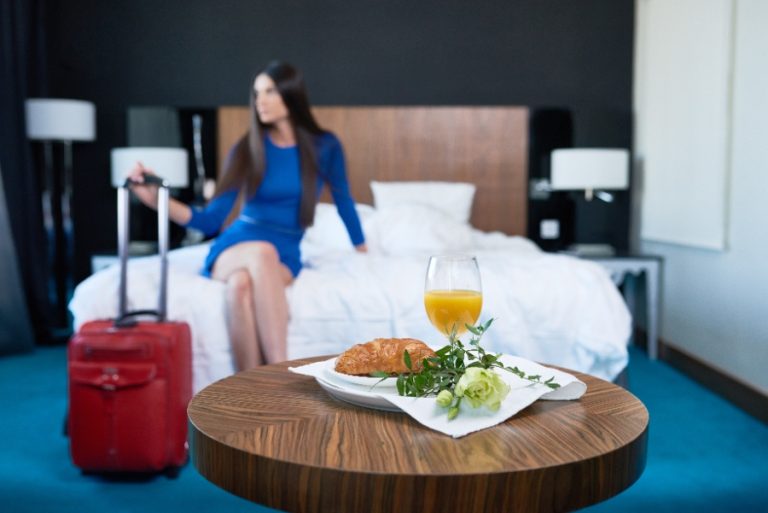 Plateau repas posé sur un lit d’hôtel avec plats chauds, couverts et serviettes soigneusement disposés