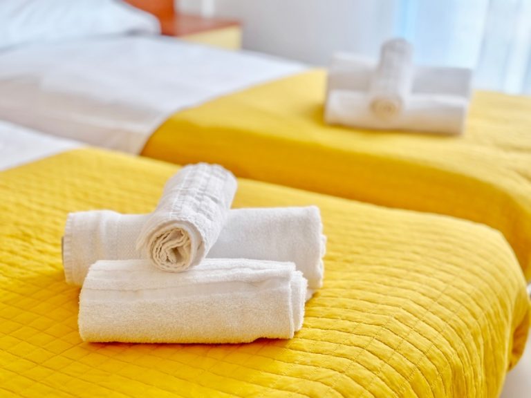 Serviette blanche épaisse et moelleuse posée sur le lit d’une chambre d’hôtel