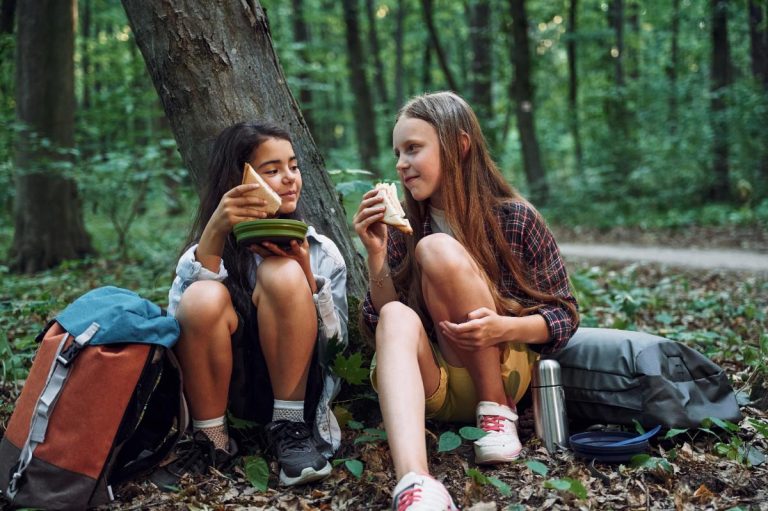 Des filles assises par terre et mangeant des pains pendant une randonnée