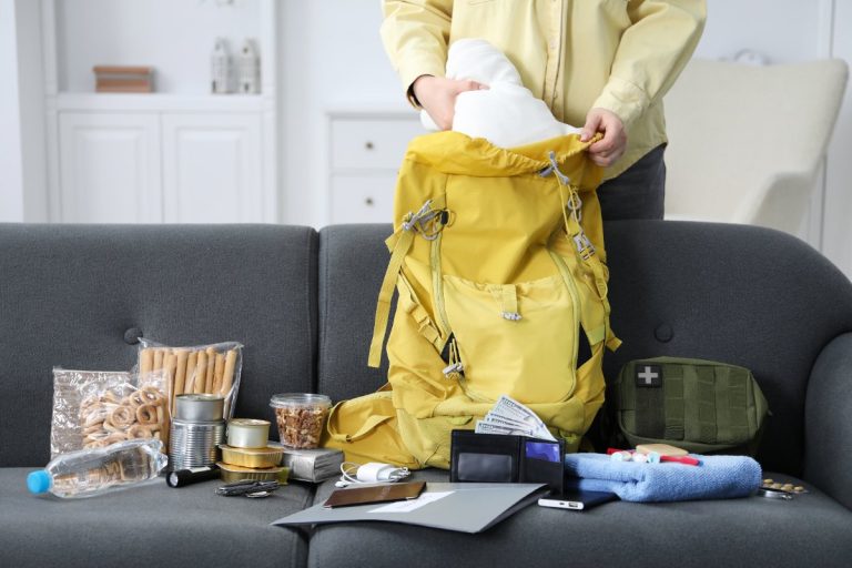 Une personne qui range ses équipements de randonnée dans un sac à dos jaune