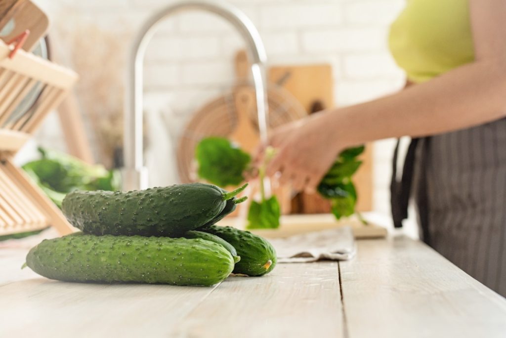 Une femme qui lave des concombres dans la cuisine