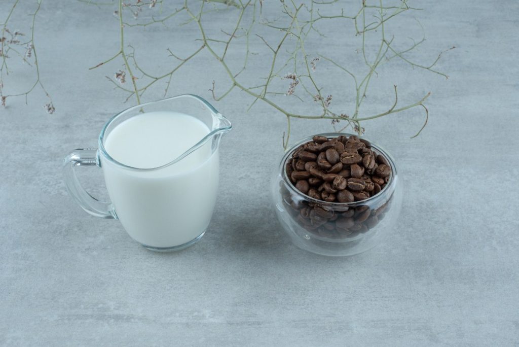 Du lait dans un verre près des grains de café