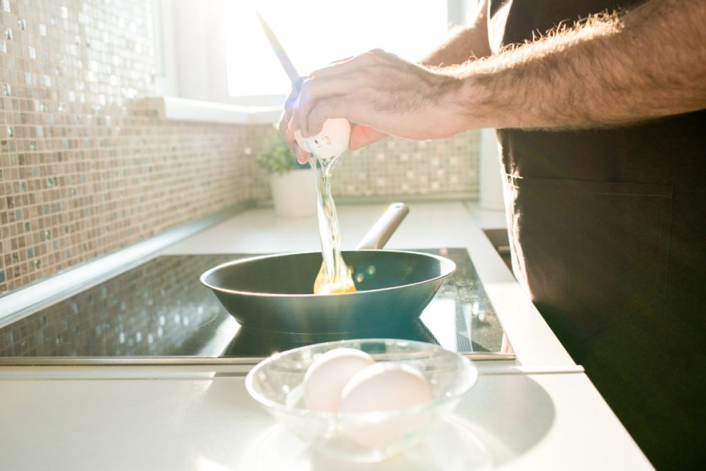 Une personne qui prépare un oeuf sur le comptoir de la cuisine
